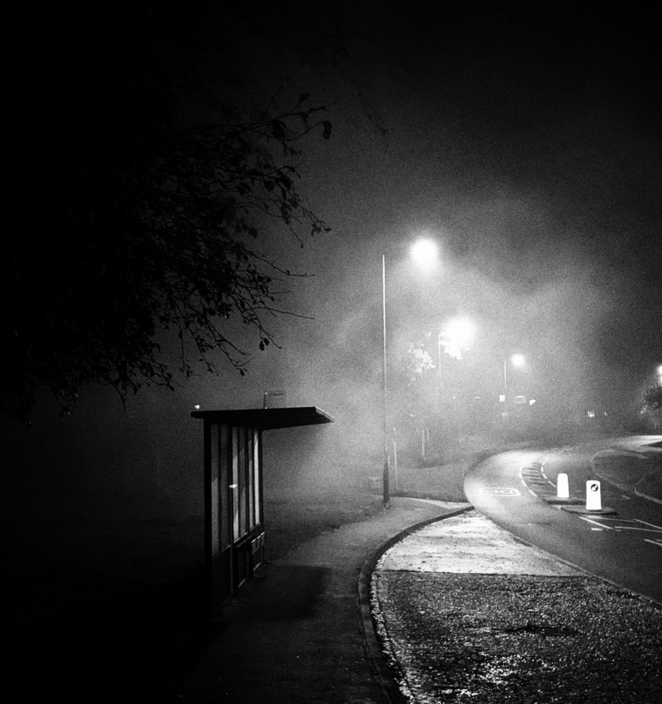 bus stop on an empty street on a murky night